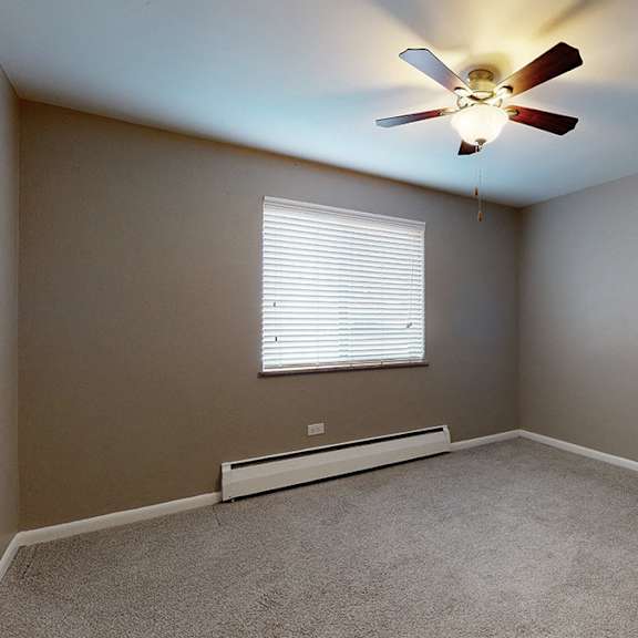 a room with a ceiling fan and a window with blinds.
