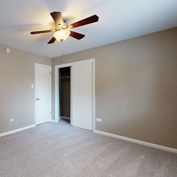 a room with a ceiling fan and carpeted floor.