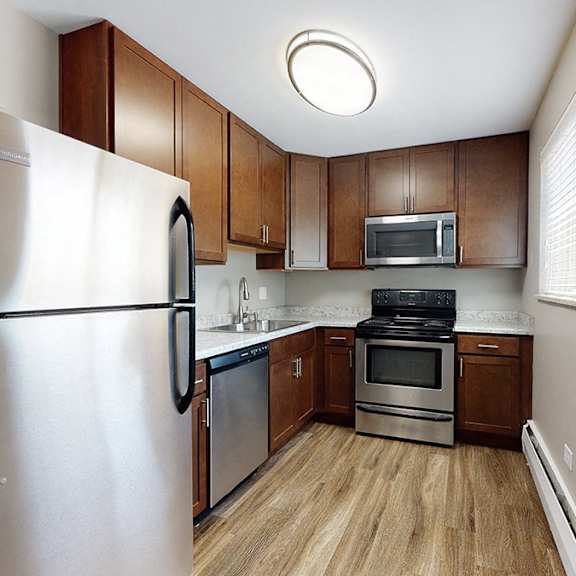a kitchen with a refrigerator, microwave, oven, and cabinets.
