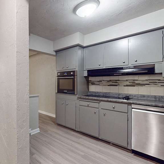 a kitchen with stainless steel appliances and wooden floors.