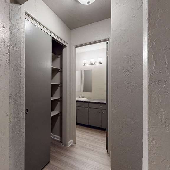 a hallway with a door on the left and a kitchen area on the right.