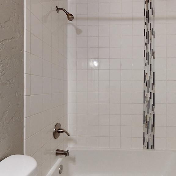 a white bathroom with a white toilet and a shower with a black and white shower curtain.