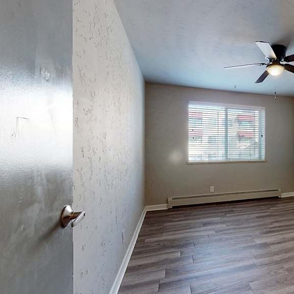 a room with a ceiling fan and a window with blinds.