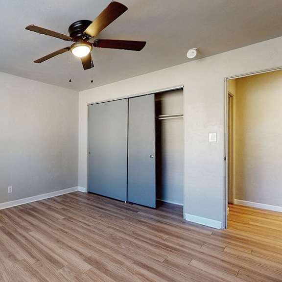 a room with a ceiling fan and wooden flooring.