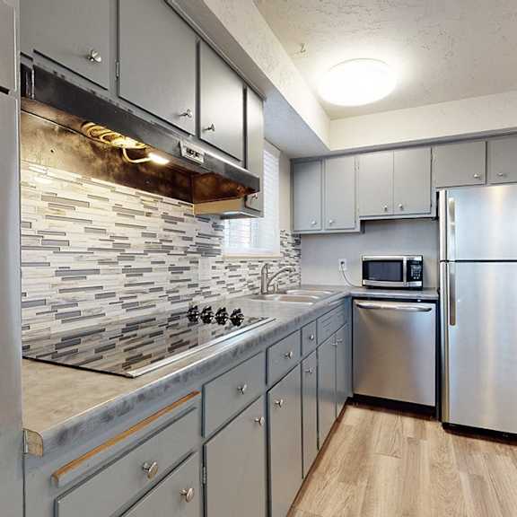 a modern kitchen with stainless steel appliances and a stone backsplash.