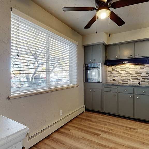 a kitchen with a white counter top and wooden floors.