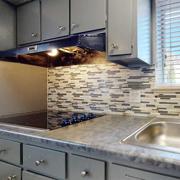 a kitchen with a stone backsplash and a double sink.
