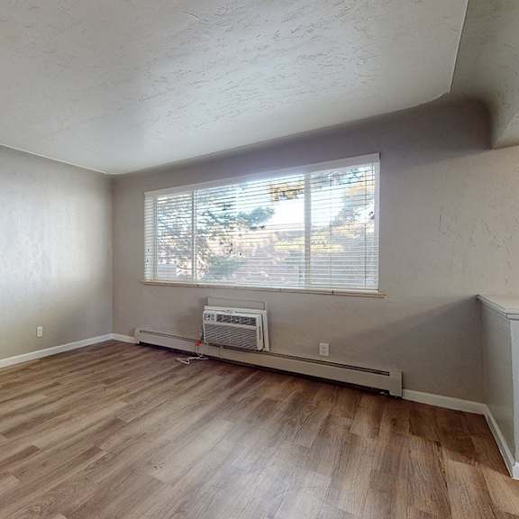 a room with wooden flooring and a window with blinds.