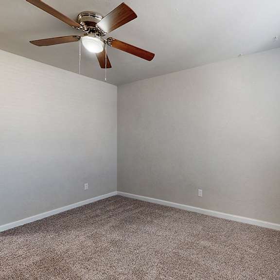 a room with a ceiling fan and carpeted floor.
