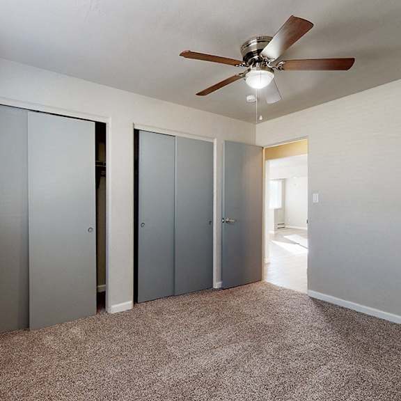 a room with a ceiling fan and three closets.