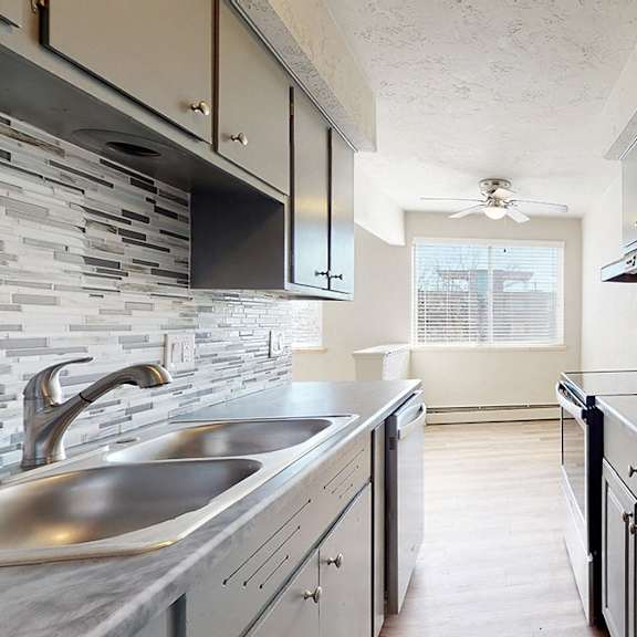 a modern kitchen with a stone backsplash and stainless steel appliances.