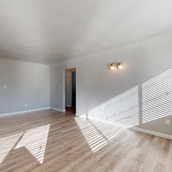 a room with wooden floors and a window with blinds.