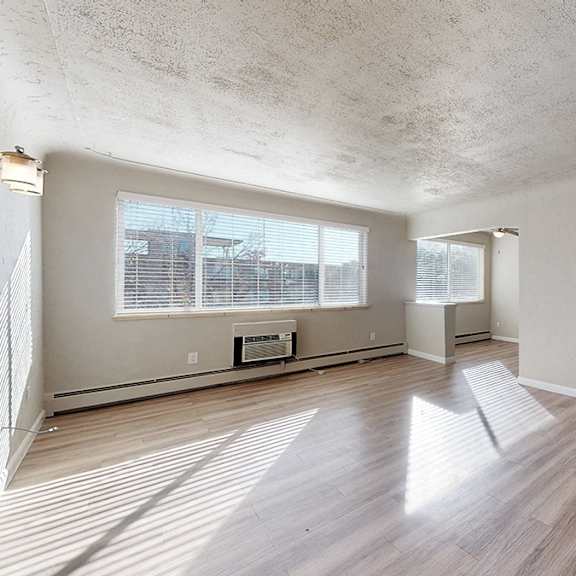 a room with wooden flooring and a window with blinds.