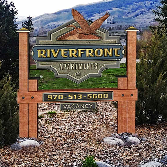 a sign for riverfront apartments with a phone number for vacancies.