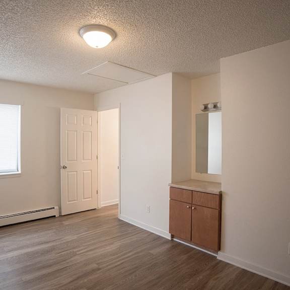 a room with a white door, a window, and a wooden floor.