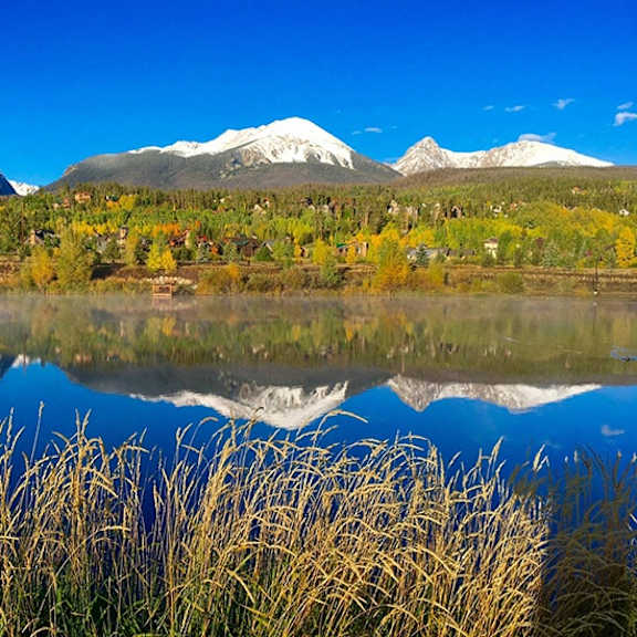 a serene landscape with a lake, grass, and mountains in the background.