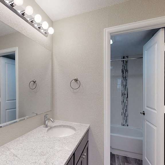 a bathroom with a sink, mirror, and lights.