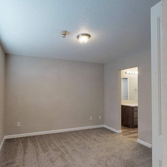 a room with a carpeted floor and a window with blinds.