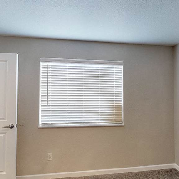 a room with a closed white door and a window with blinds.