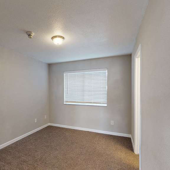 a room with a carpeted floor and a window with blinds.
