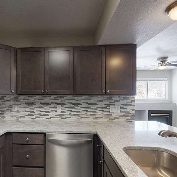 a kitchen with dark brown cabinets and a stainless steel dishwasher.