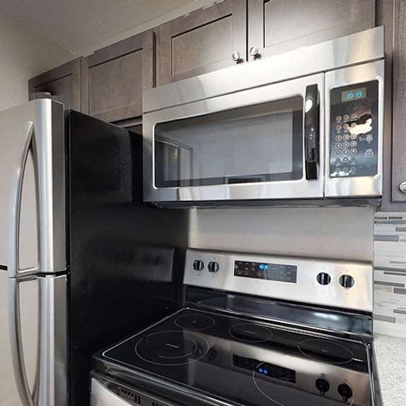 a modern kitchen with a stainless steel refrigerator, microwave, and oven.