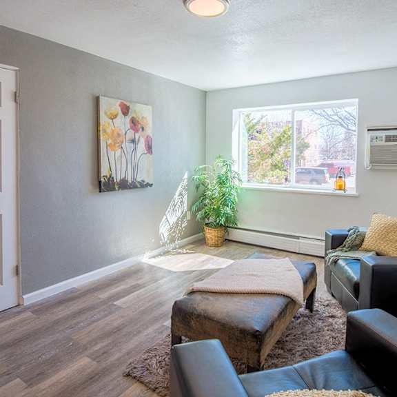 a living room with a white door, a brown couch, and a painting on the wall.