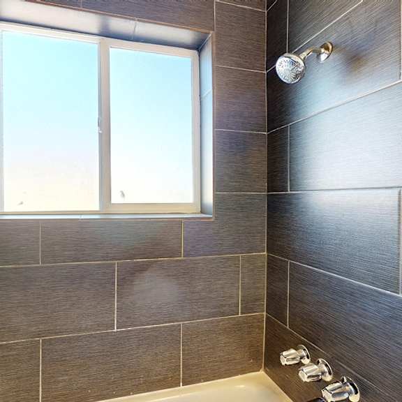 a bathroom with a window and tiled walls.