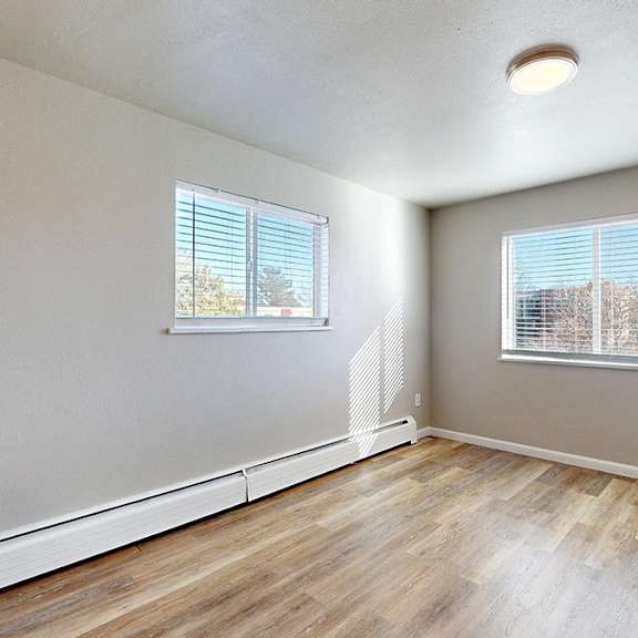 a room with wooden floors and two windows.