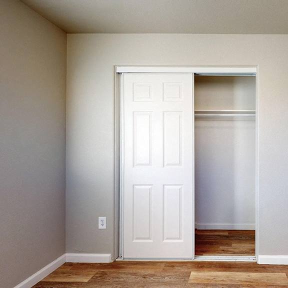 a white door is open in a room with a brown floor.