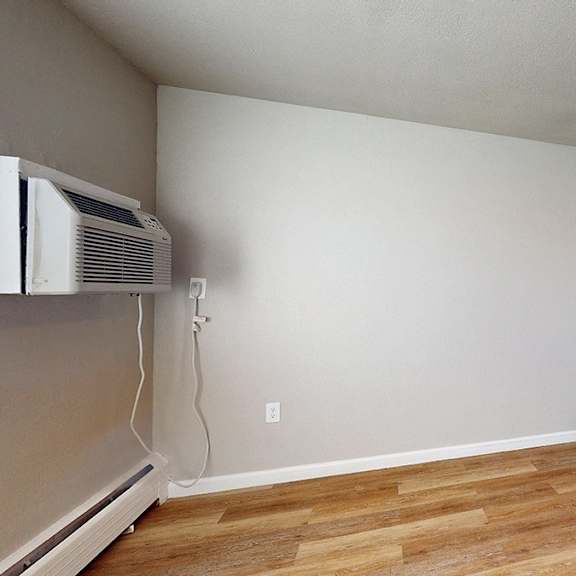 a room with wooden floors and a white wall with a window.