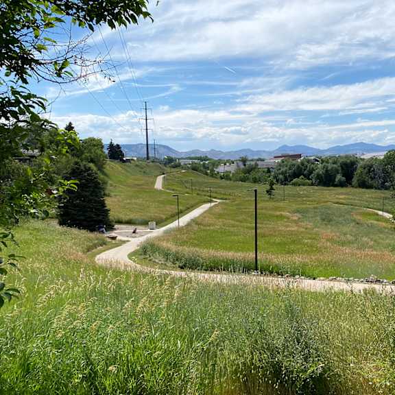 view of mountains from sunset park. grassy field in distance with concrete trail.