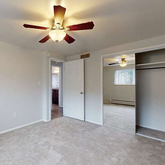 bedroom with a ceiling fan, carpeted floor and closet with sliding door.