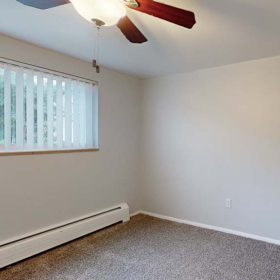 a room with a ceiling fan and a window with blinds.