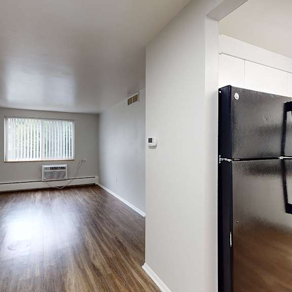 a black fridge in a kitchen with white cabinets.