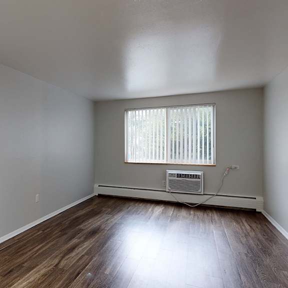 a room with wooden floors and a window with blinds.