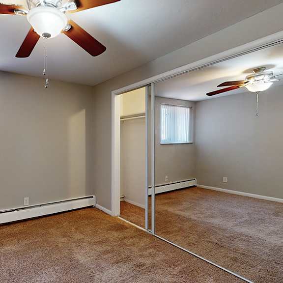 a room with a ceiling fan and a window with blinds.