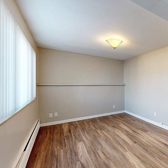 a room with wooden flooring and a window on the left side.