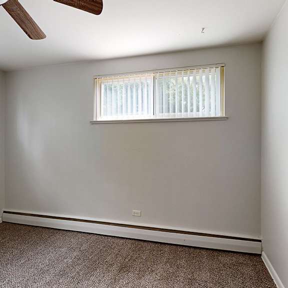 a room with a ceiling fan and two windows.