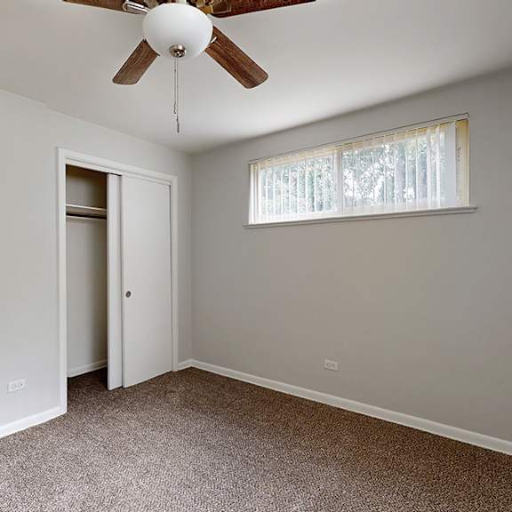 a room with a ceiling fan and a window with blinds.
