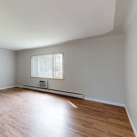 a room with wooden flooring and a window with blinds.