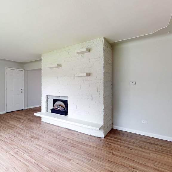 a white room with a fireplace and wooden floors.