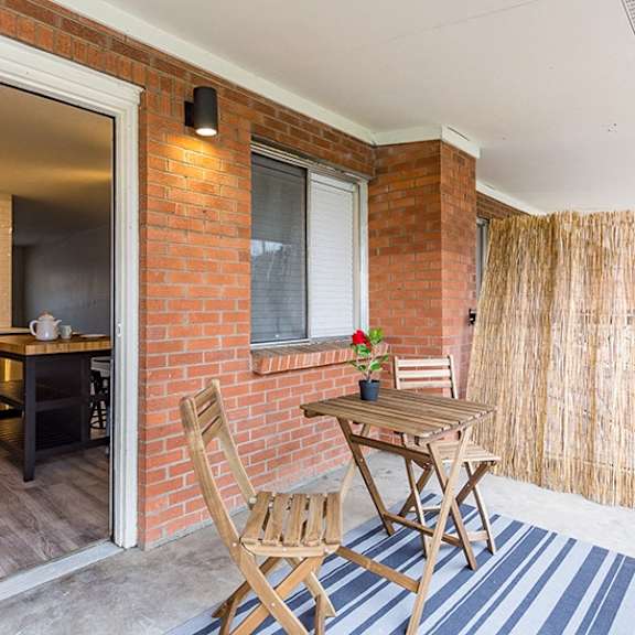 a wooden chair is placed in front of a brick wall.