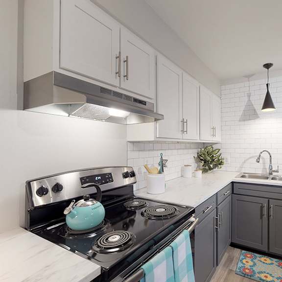 a modern kitchen with a black stove top oven and white cabinets.
