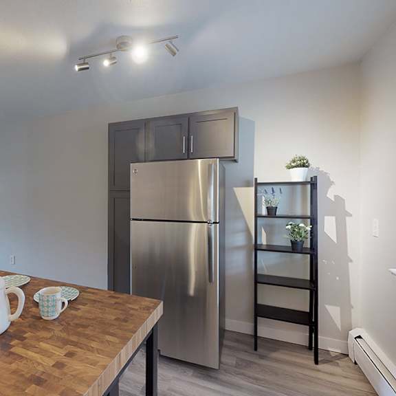 a kitchen with a wooden table and a stainless steel refrigerator.
