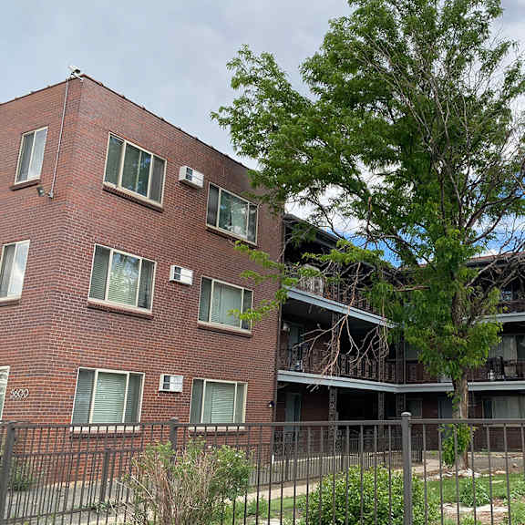 a red brick apartment building with a tree in front.