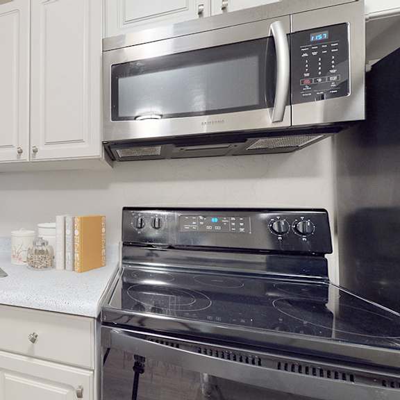 a modern kitchen with a stainless steel oven and white cabinets.
