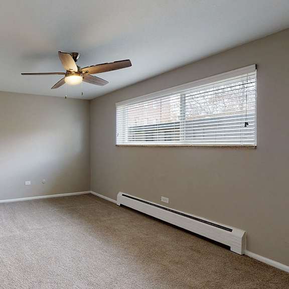a room with a ceiling fan and a window with blinds.