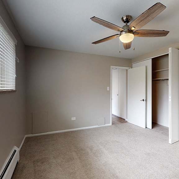 a room with a ceiling fan and a window with blinds.