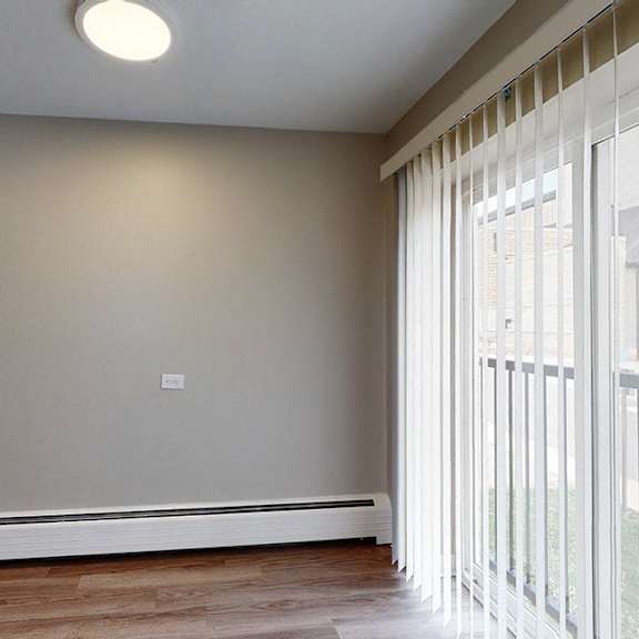a room with a window covered by white blinds and a wall-mounted air conditioner.